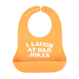 Bella Tunno I Laugh at Dad Jokes Wonder Bib in orange, featuring a "I Laugh at Dad Jokes" design, adjustable neck, and a catch pocket, made from BPA-free silicone, available at Be Charmed