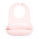Bella Tunno "Little Sis" Wonder Bib in pink, featuring a generous catch pocket and adjustable neck closure, available at Be Charmed.