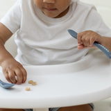 Child with Bella Tunno Hangry Mister Mess Spoon in soft blue, featuring a beaded design and "HANGRY" message, made from BPA-free silicone, available at Be Charmed