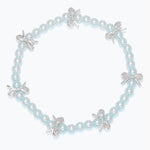 Kids bracelet with light blue pearls and silver bow charms on a white background. Available at Be Charmed.