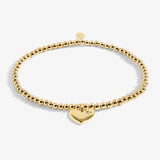 Gold bracelet with a heart-shaped charm on a white background. Available at Be Charmed