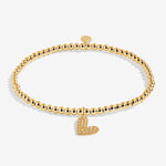 Gold bracelet with a heart charm on a white background. Available at Be Charmed