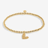 Gold bracelet with a heart charm on a white background. Available at Be Charmed