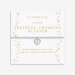 Silver bracelet with heart charm on a white card with gold text. Available at Be Charmed