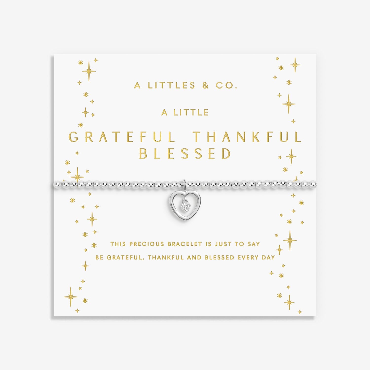 Silver bracelet with heart charm on a white card with gold text. Available at Be Charmed