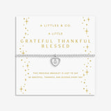 Silver bracelet with heart charm on a white card with gold text. Available at Be Charmed