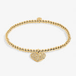 Gold bracelet with a heart-shaped charm on a white background. Available at Be Charmed