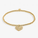 Gold bracelet with a heart-shaped charm on a white background. Available at Be Charmed