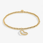 Gold bracelet with a heart-shaped charm on a white background. Available at Be Charmed