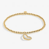 Gold bracelet with a heart-shaped charm on a white background. Available at Be Charmed
