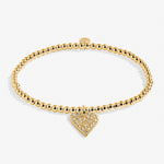 Gold bracelet with a heart-shaped charm on a white background. Available at Be Charmed