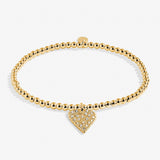 Gold bracelet with a heart-shaped charm on a white background. Available at Be Charmed