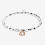 Silver bracelet with a heart-shaped rose gold charm on a white background. Available at Be Charmed