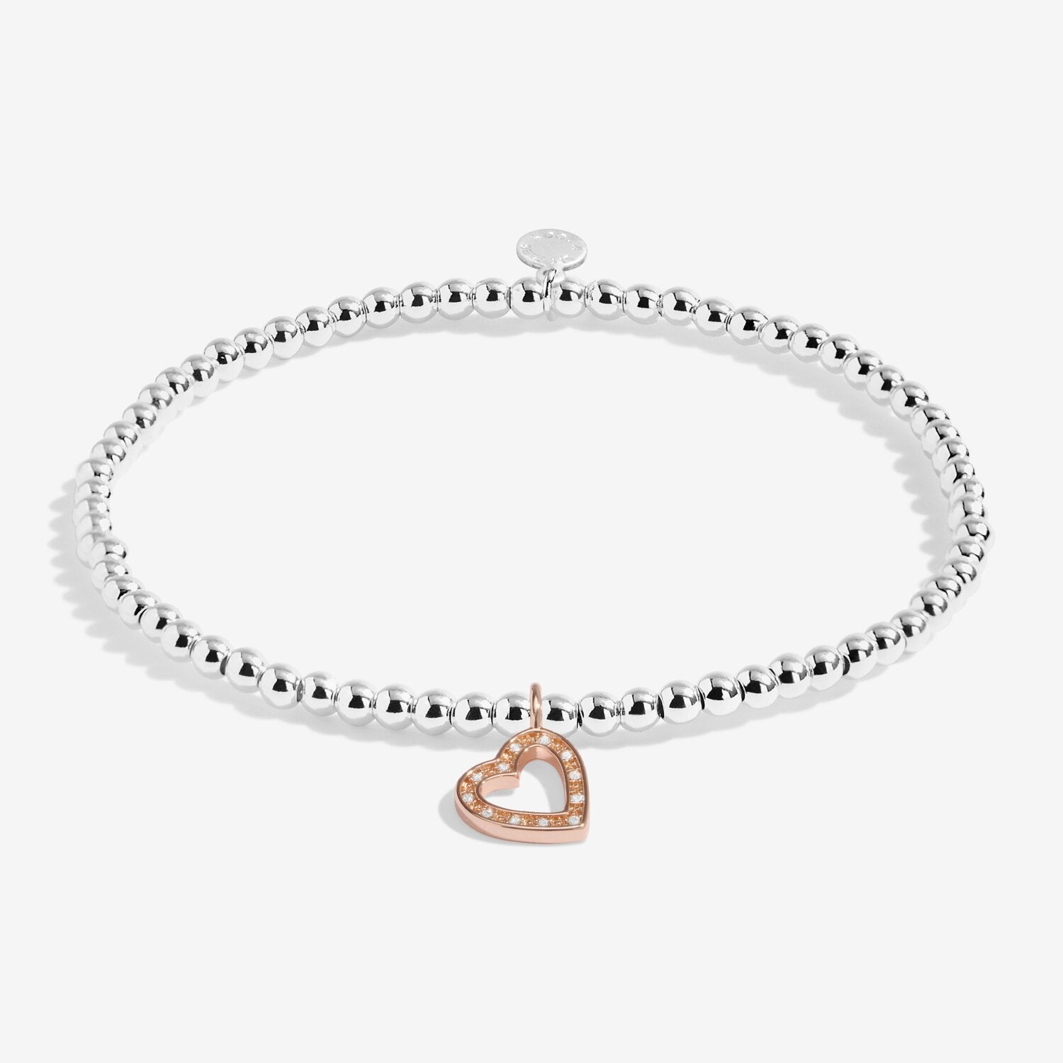 Silver bracelet with a heart-shaped rose gold charm on a white background. Available at Be Charmed
