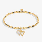 Gold bracelet with a heart charm on a white background. Available at Be Charmed