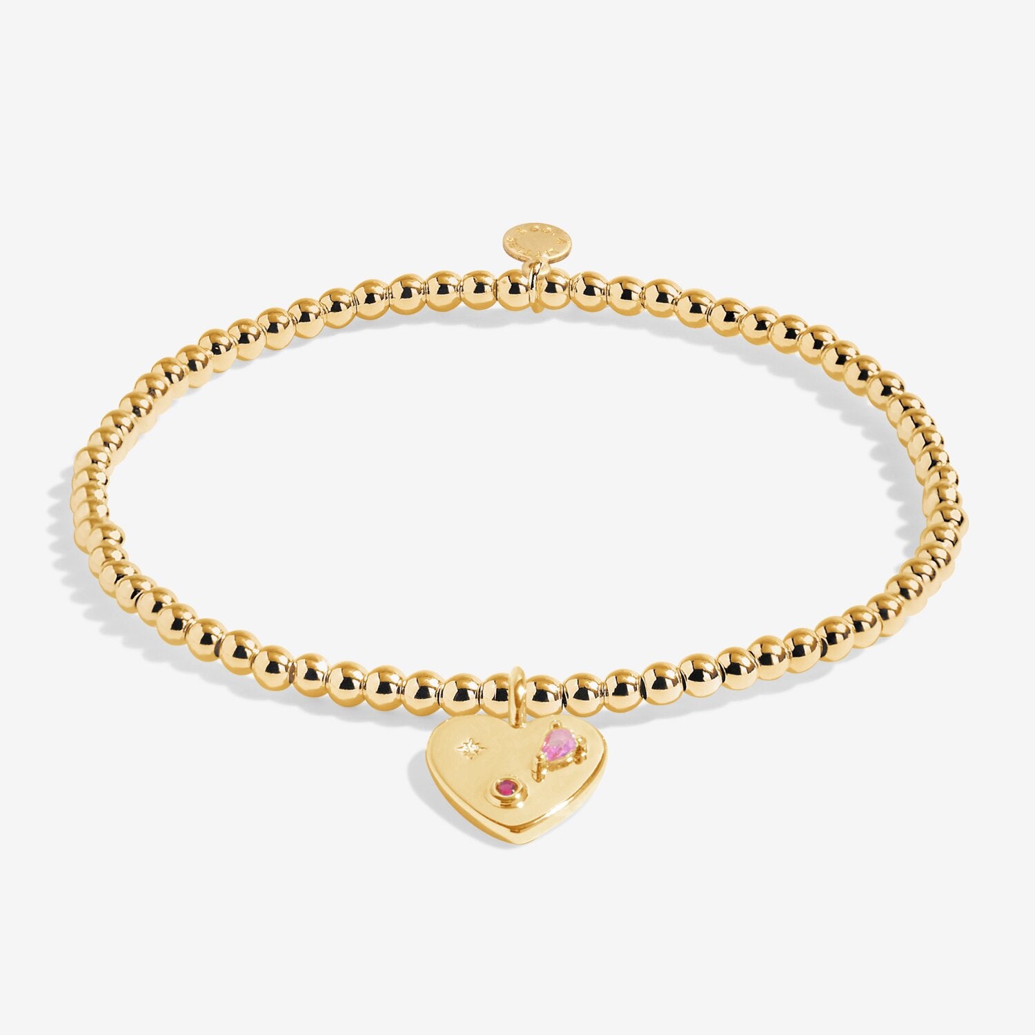 Gold bracelet with a heart-shaped tag featuring a pink gemstone on a white background. Available at Be Charmed