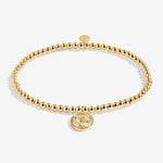 Gold beaded bracelet with a round charm on a white background. Available at Be Charmed