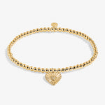Gold bracelet with a heart-shaped charm on a white background. Available at Be Charmed