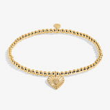 Gold bracelet with a heart-shaped charm on a white background. Available at Be Charmed