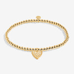 Gold bracelet with a heart-shaped charm on a white background. Available at Be Charmed