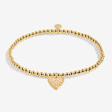 Gold bracelet with a heart-shaped charm on a white background. Available at Be Charmed