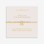 A Littles & Co Gold bracelet with champagne glass charm on a pink card with text. Available at Be Charmed