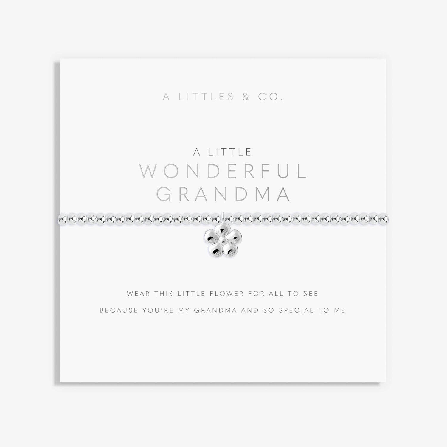 Silver bracelet with a heart charm on a white card with text, displayed on a light gray background. Available at Be Charmed