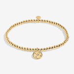 Gold bracelet with a round charm on a white background. Available at Be Charmed