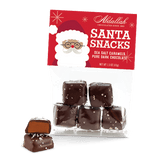 Packaging for Abdallah Santa Snacks which are sea salt caramels in dark chocolate, displayed with a Santa Claus figure in the background. Available at Be Charmed