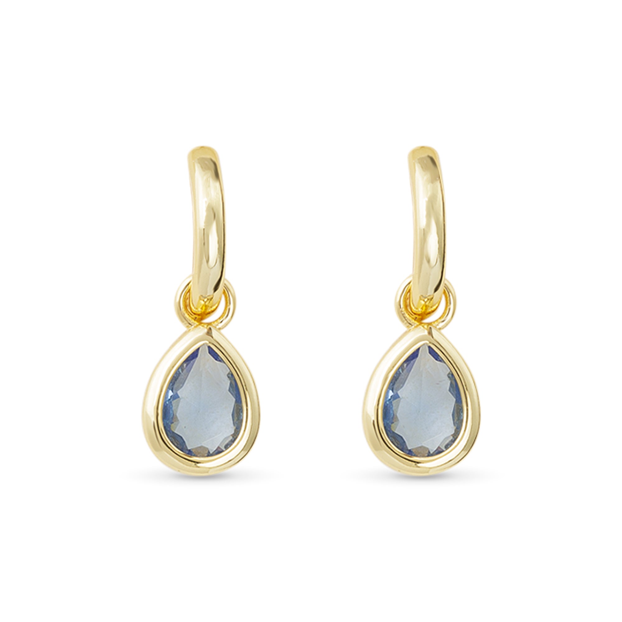 Gold earrings with teardrop-shaped blue gemstones on a white background. Avaiable at Be Charmed
