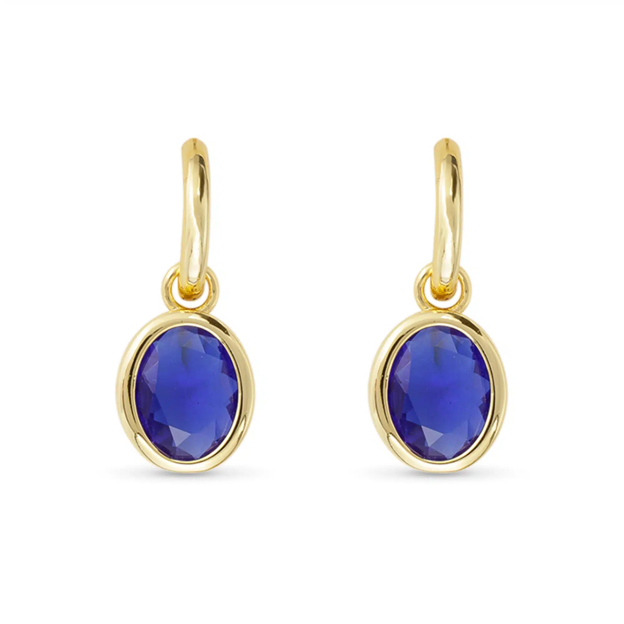Gold earrings with blue gemstones on a white background. Available at Be Charmed