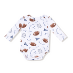 Baby onesie with football pattern on a white background. Available at Be Charmed. 