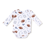 Baby onesie with football pattern on a white background. Available at Be Charmed. 