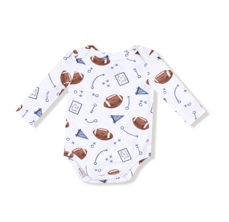 Baby onesie with football pattern on a white background. Available at Be Charmed. 