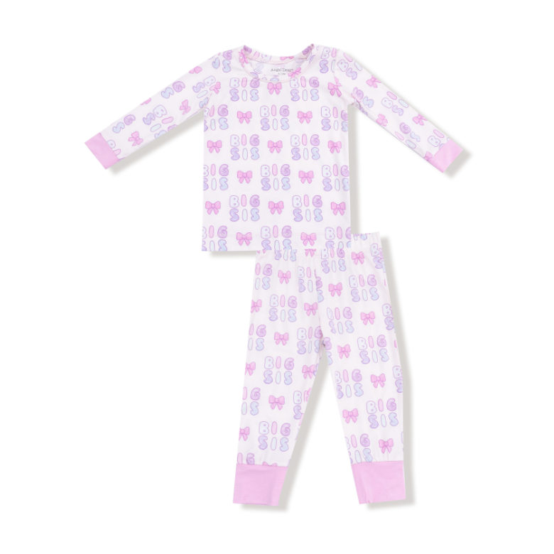 Children's pajama set with "Big Sis" and bow pattern on a white background. Available at Be Charmed.