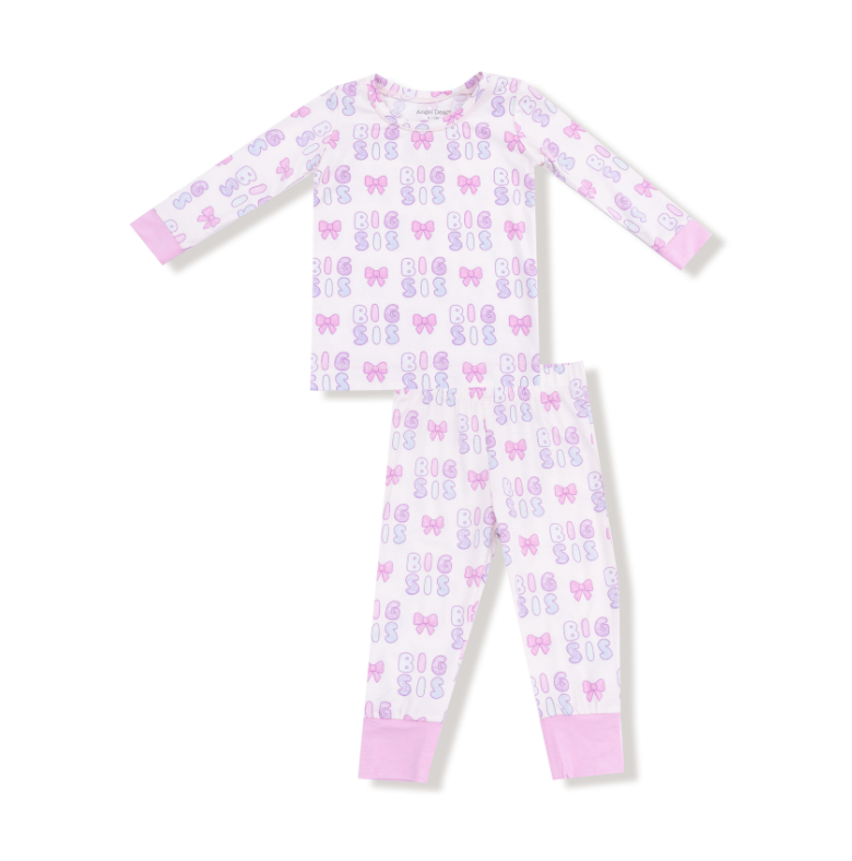 Children's pajama set with "Big Sis" and bow pattern on a white background. Available at Be Charmed.