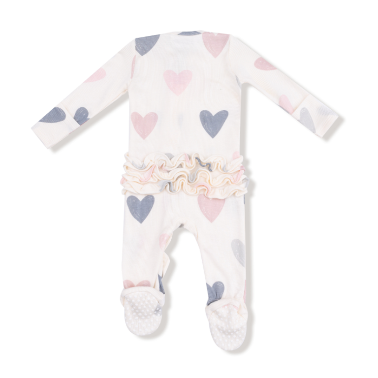 Baby onesie with heart patterns on a white background. Available at Be Charmed. 