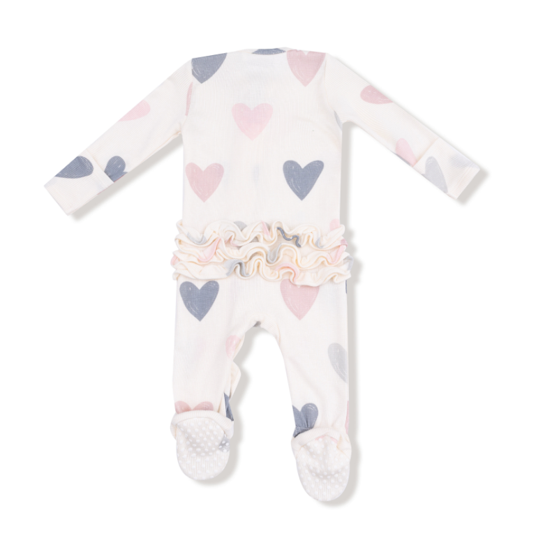Baby onesie with heart patterns on a white background. Available at Be Charmed. 