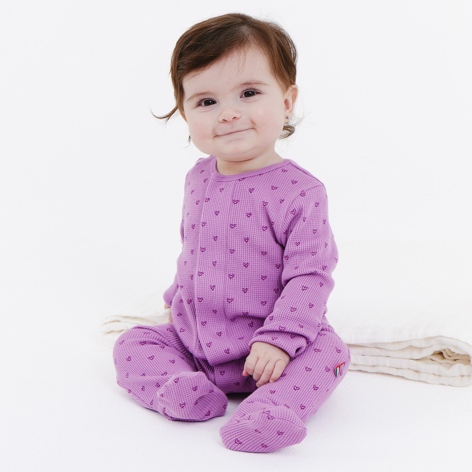 Baby wearing a Magnetic Me waffle fabric footie in Pink Ribbon, available at Be Charmed.
