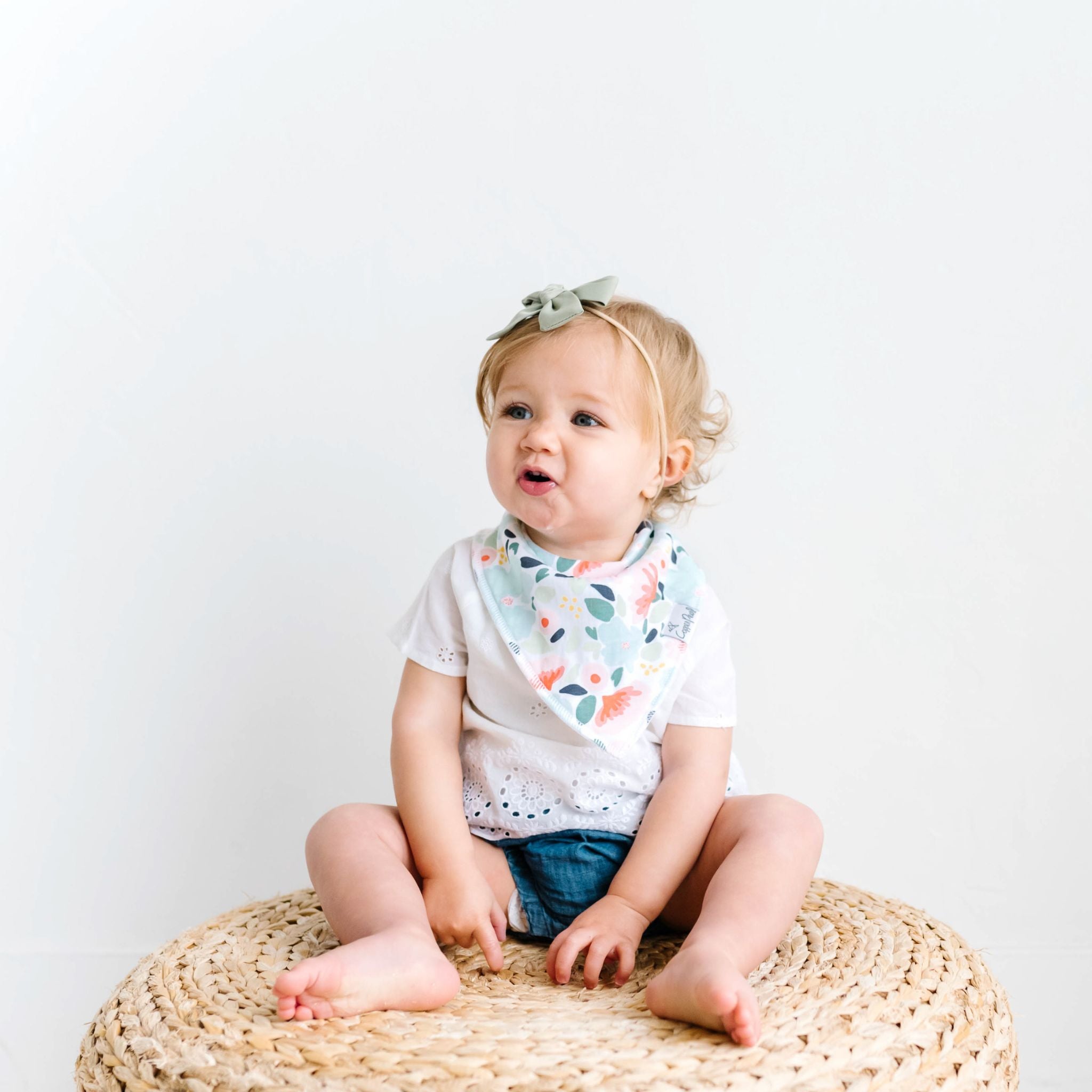 Baby wearing a Copper Pearl Leilani Bandana Bib Set bib featuring absorbent cotton front and soft fleece back, adjustable for babies 0-36 months. Available at Be Charmed.
