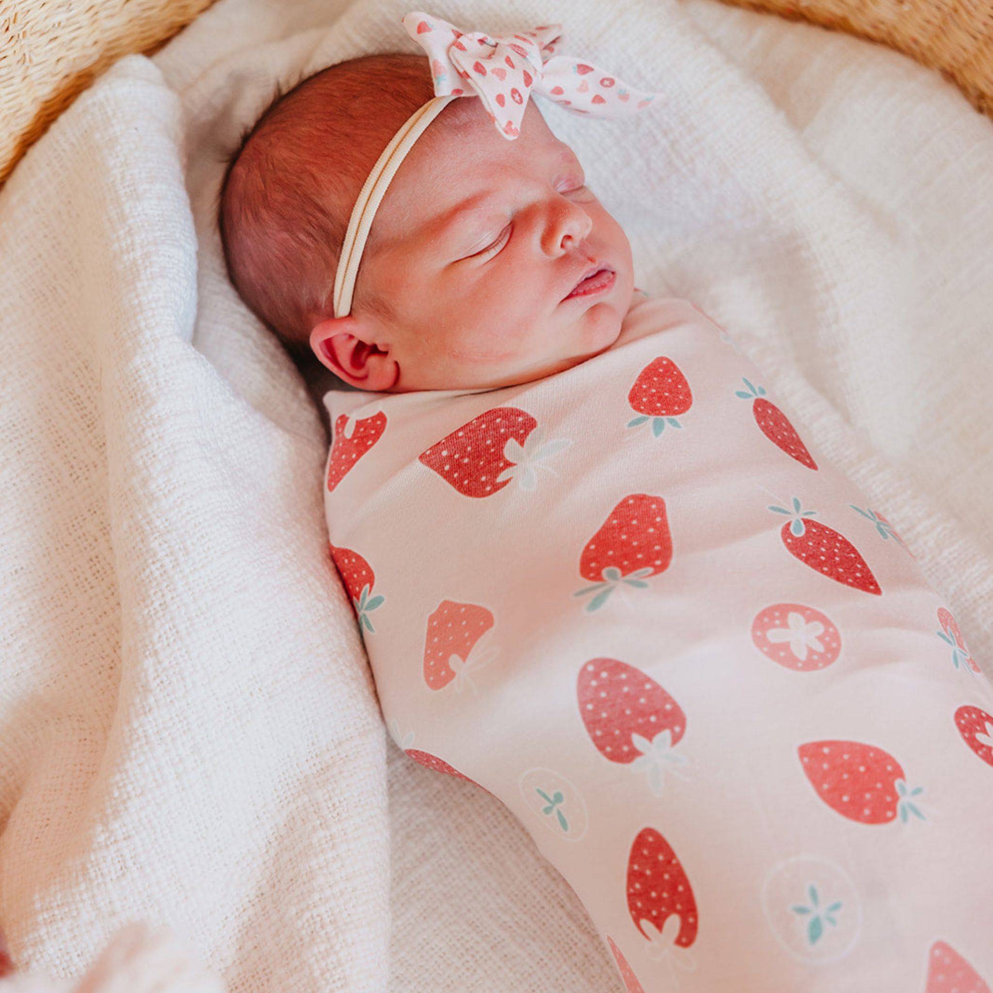 Baby in Copper Pearl Strawberry Knit Swaddle Blanket featuring soft, breathable, and stretchy fabric, perfect for newborns. Available at Be Charmed.