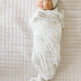 Baby wrapped with Gage print knit swaddle blanket by Copper Pearl featuring soft breathable knit fabric in neutral stripes, perfect for swaddling and tummy time—Available at Be Charmed