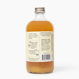 Bottle of liquid with a label on a white background. Available at Be Charmed