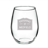 A clear glass wine glass with 'ENTERING MEDFIELD 1649' printed in black text near the base, representing the year the town was established. Available at Be Charmed