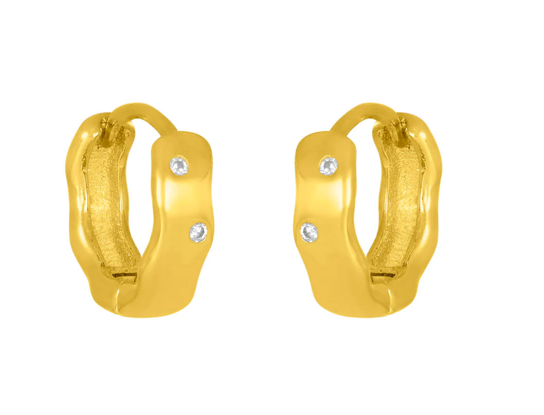 A pair of gold-colored huggie earrings with sparkling cubic zirconia set within. Available at Be Charmed