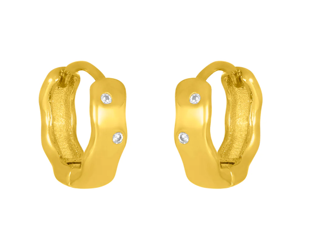A pair of gold-colored huggie earrings with sparkling cubic zirconia set within. Available at Be Charmed