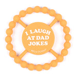 Bella Tunno "I Laugh at Dad Jokes" Teether in orange, featuring a beaded texture and easy-grip design, available at Be Charmed.
