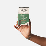 Hand holding a box of Big Heart Teas Cozy Night tea against a white background. Available at Be Charmed