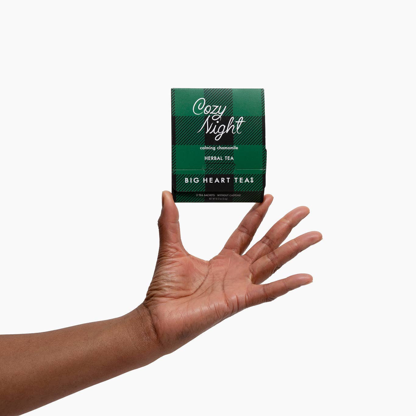 Hand holding a box of Cozy Night herbal tea from Big Heart Teas on a white background. Available at Be Charmed