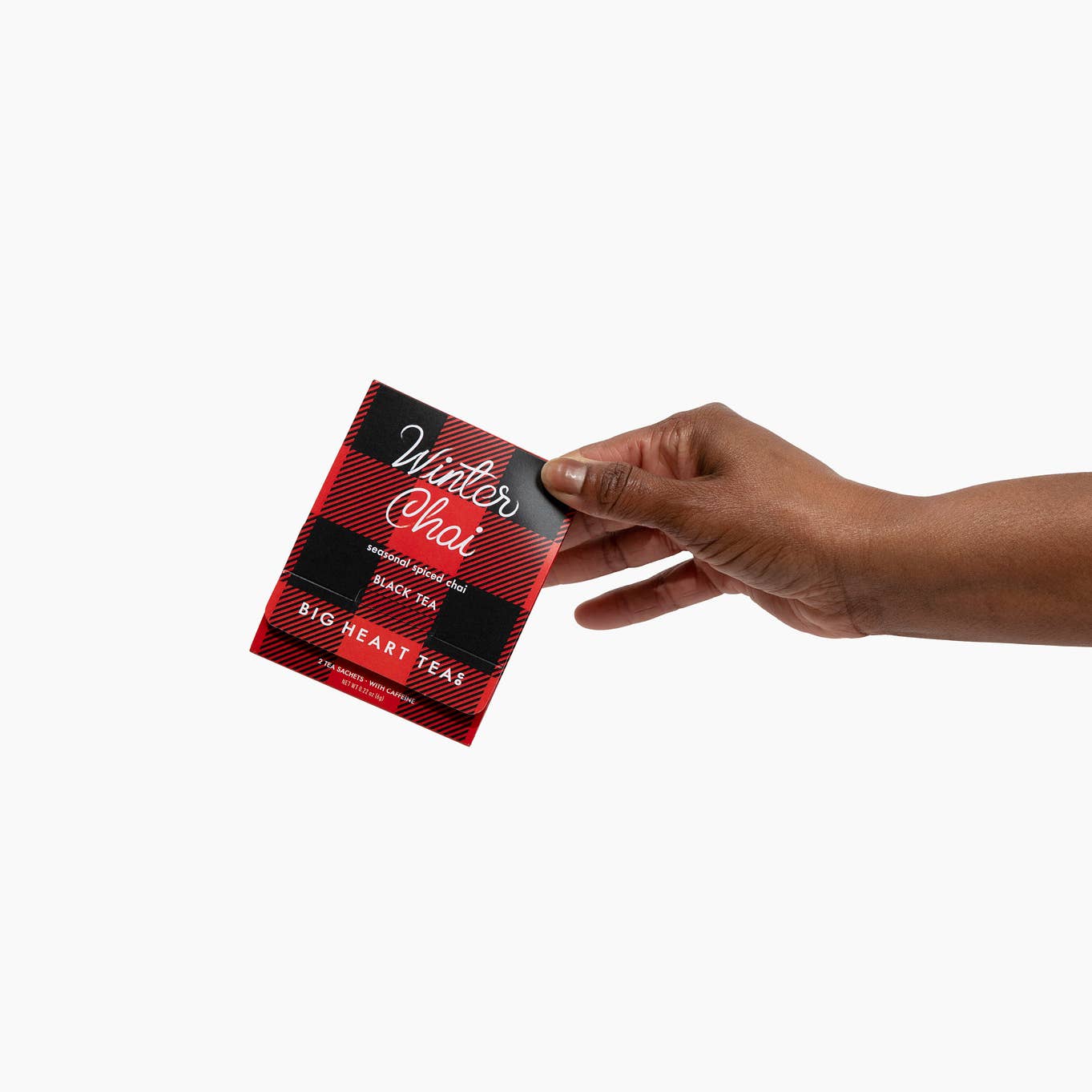 Hand holding a 'Winter Chai' tea package against a white background.  Available at Be Charmed